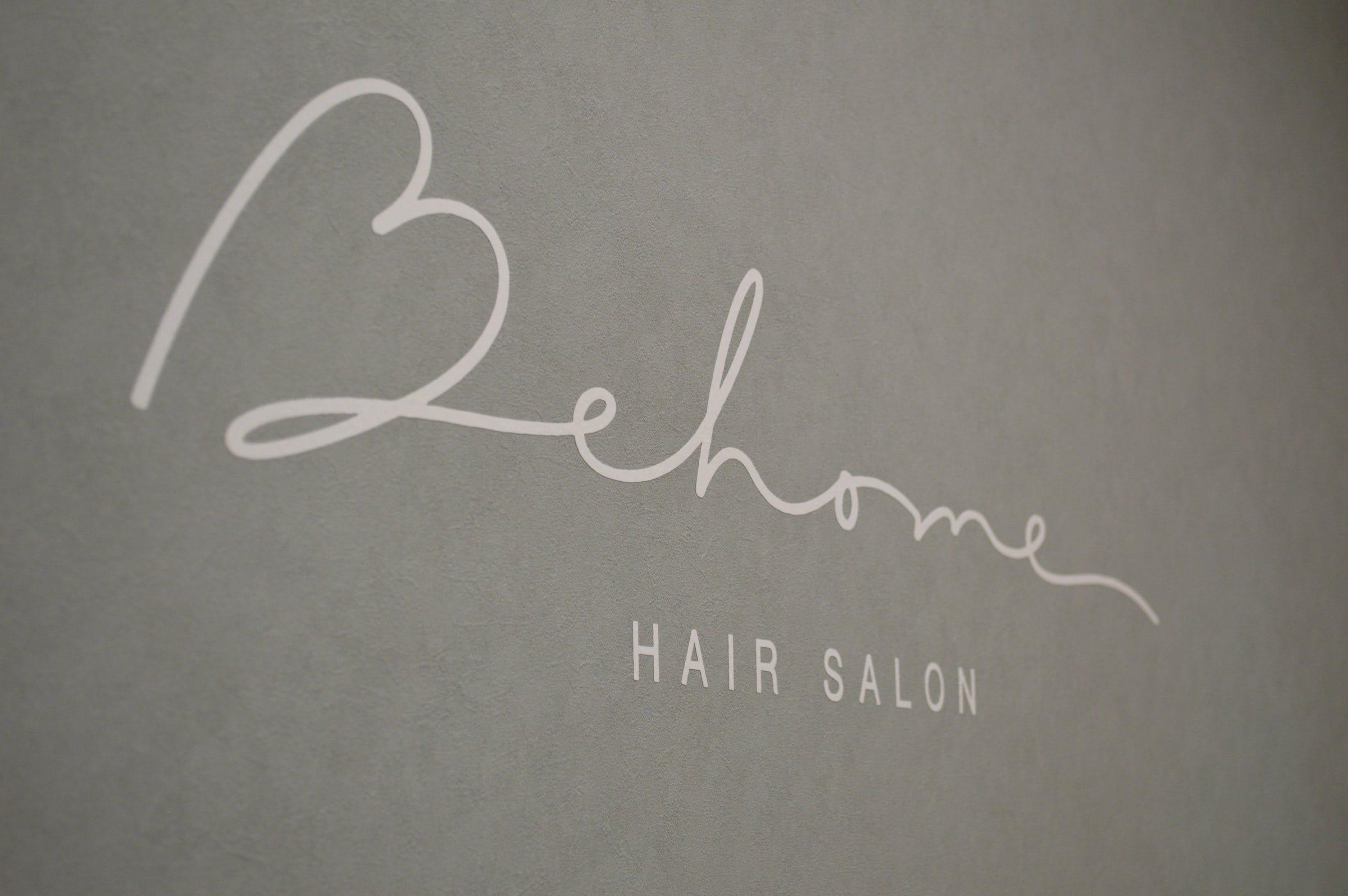 Behome の店内の壁に書かれた、Behome HAIR SALON のロゴ